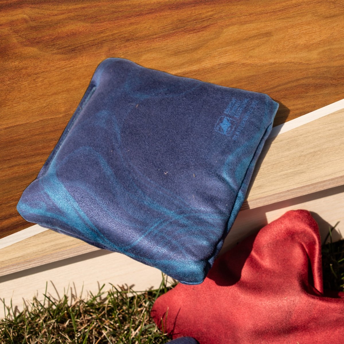 Classic Blue Lock Shot Cornhole Bags resting on an ACA cornhole board before gameplay, designed for control, blocking, and keeping more bags on the board.