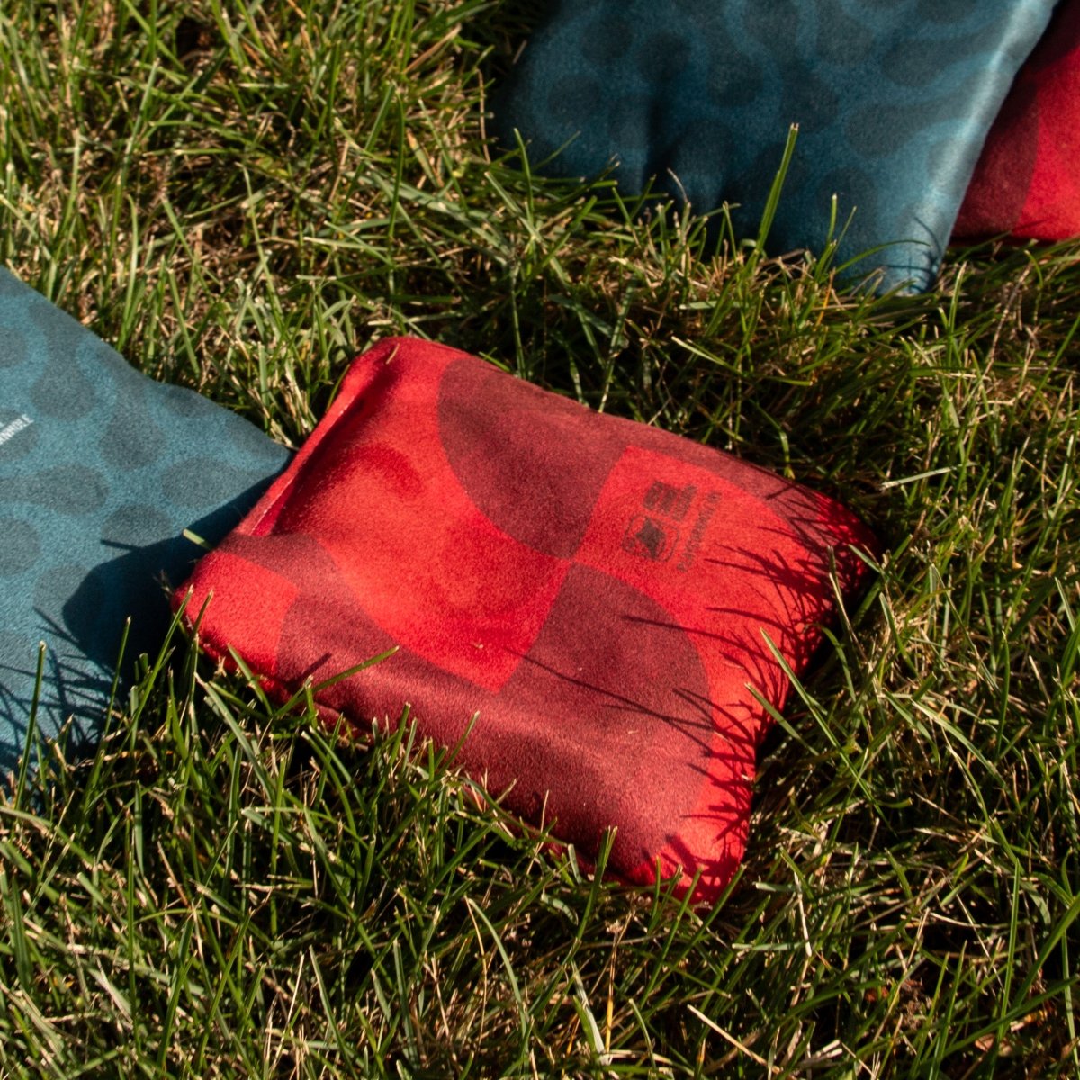 Red Fusion Lock Shot Cornhole Bags resting on an ACA cornhole board before gameplay, designed for control, blocking, and keeping more bags on the board.