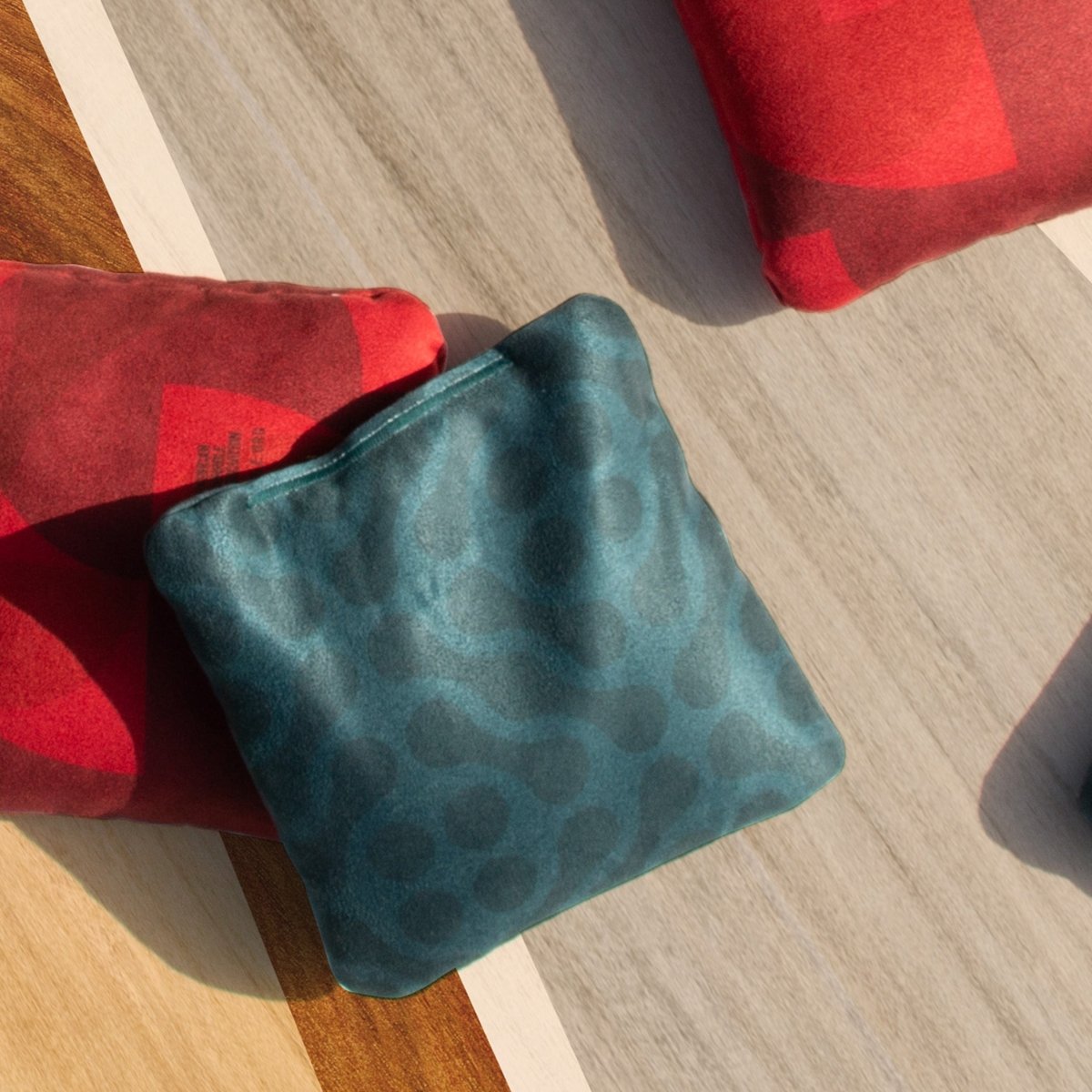 Wavy Teal Lock Shot Cornhole Bags resting on an ACA cornhole board before gameplay, designed for control, blocking, and keeping more bags on the board.